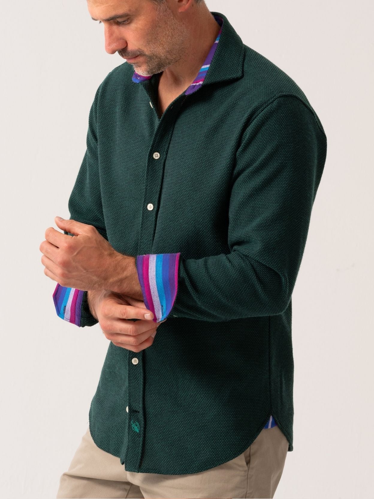 Man wearing a green shirt with a colorful collar against a white background