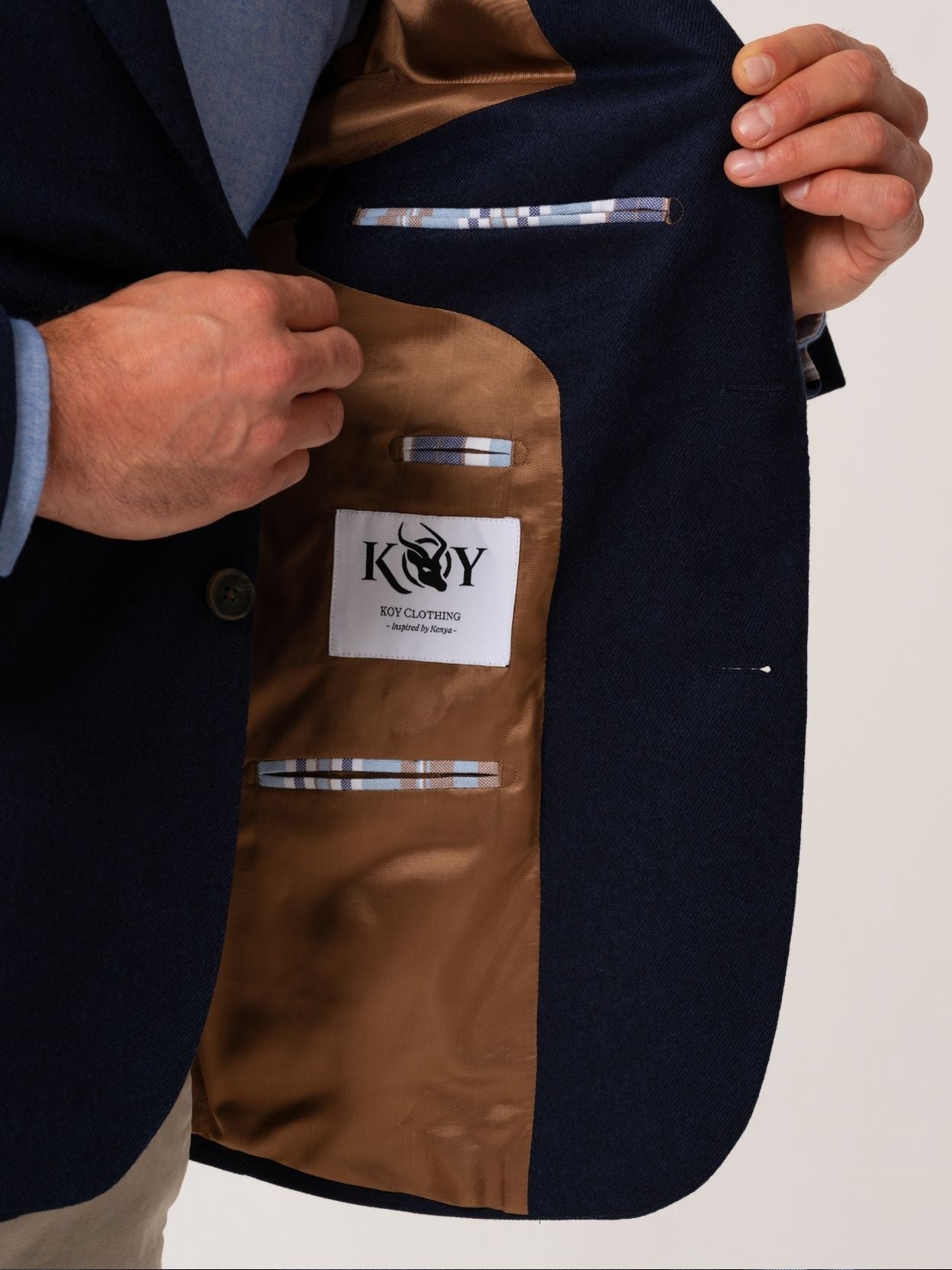 Close up of man wearing a navy wool and cashmere showing the contrast lining on a plain background