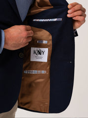 Close up of man wearing a navy wool and cashmere showing the contrast lining on a plain background