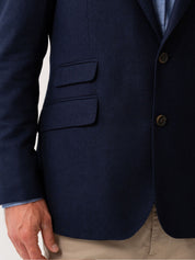 Navy blue blazer with two buttons and two flap ticket pockets on a light background