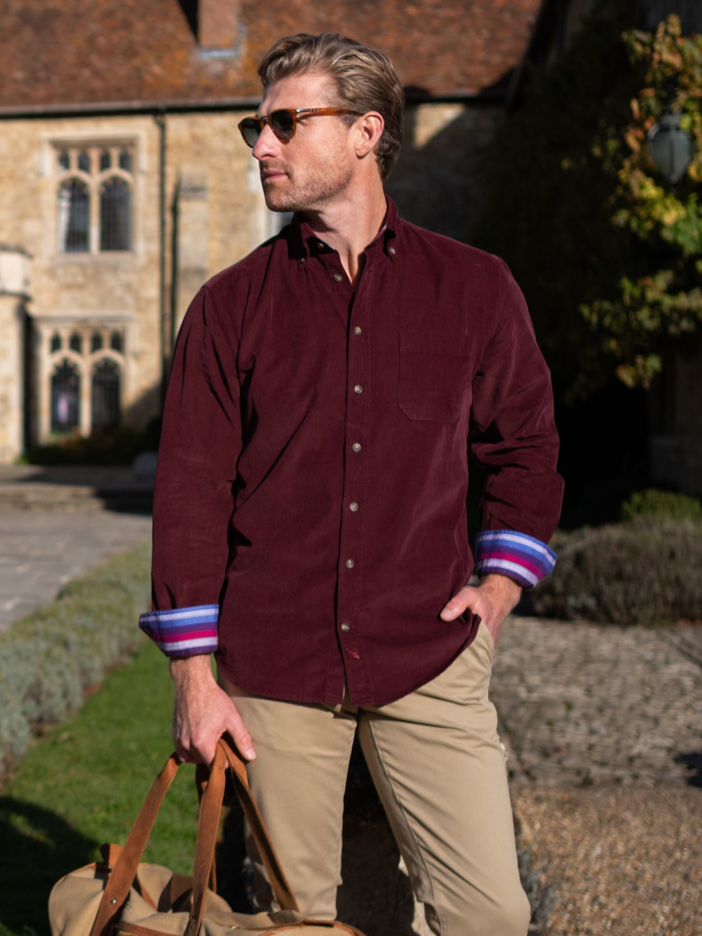 Man wearing a burgundy corduroy shirt with colourful cuffs in an outdoor setting.
