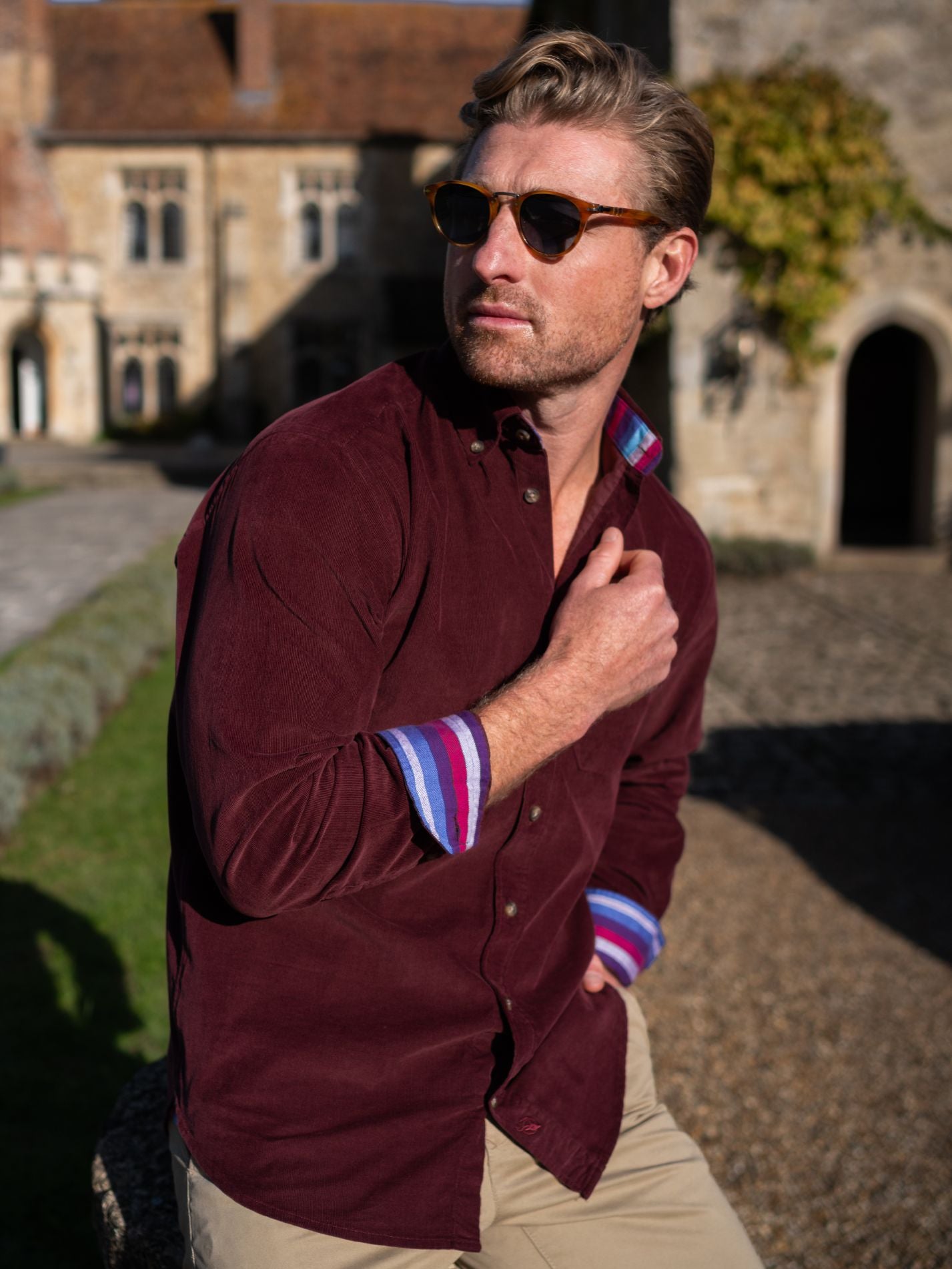 Man wearing a burgundy corduroy shirt with colourful cuffs in an outdoor setting.