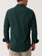 Back view of a green shirt worn by a person on a white background