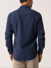 Man wearing a blue shirt from behind on a plain background