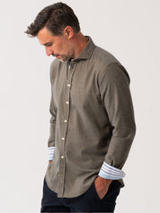 Man wearing an Olive Cotton-Cashmere button-up shirt with rolled-up sleeves on a light gray background