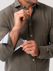 Man wearing an olive cotton-cashmere button-up shirt with rolled-up sleeves on a plain background