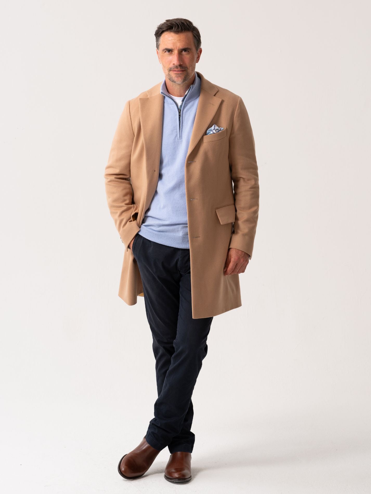 Men’s camel wool overcoat with notch lapel, worn over light blue quarter-zip jumper