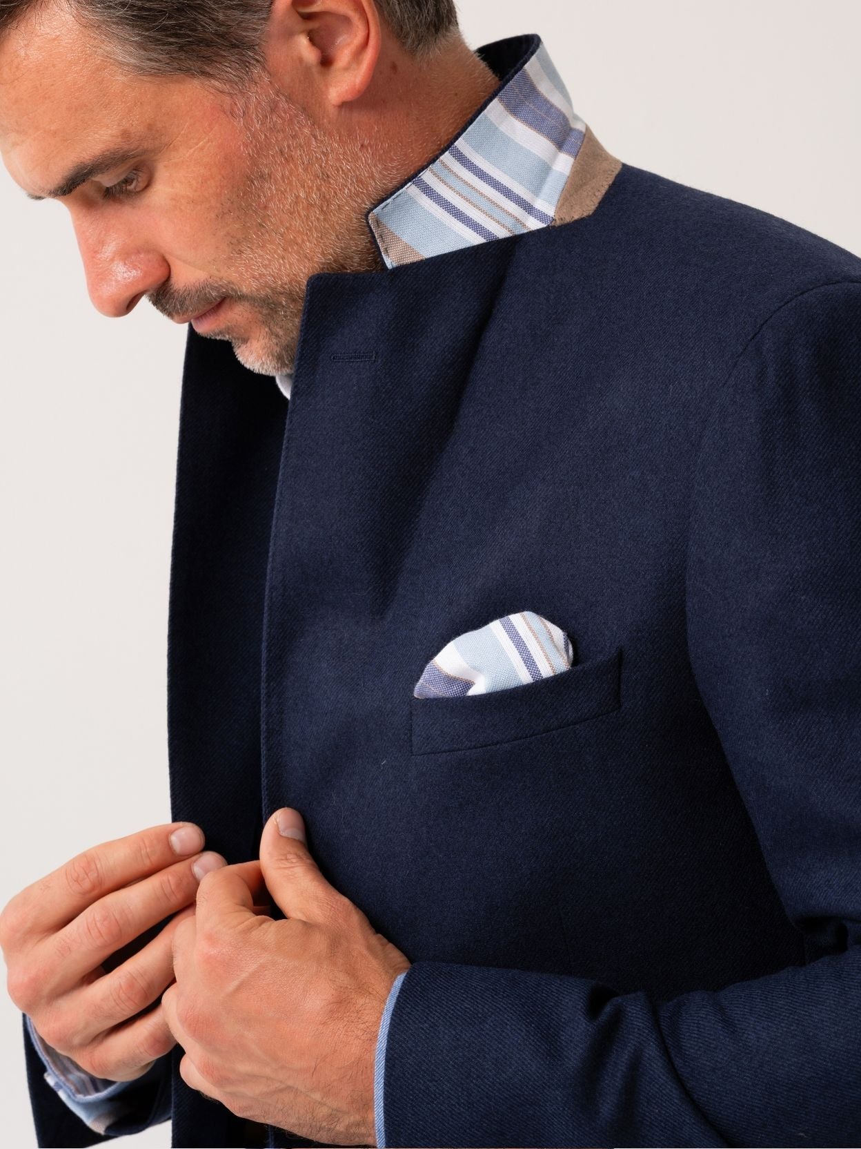 Man wearing a navy wool and cashmere blazer with striped African fabric detail on a plain background