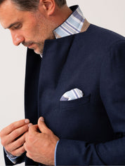 Man wearing a navy wool and cashmere blazer with striped African fabric detail on a plain background