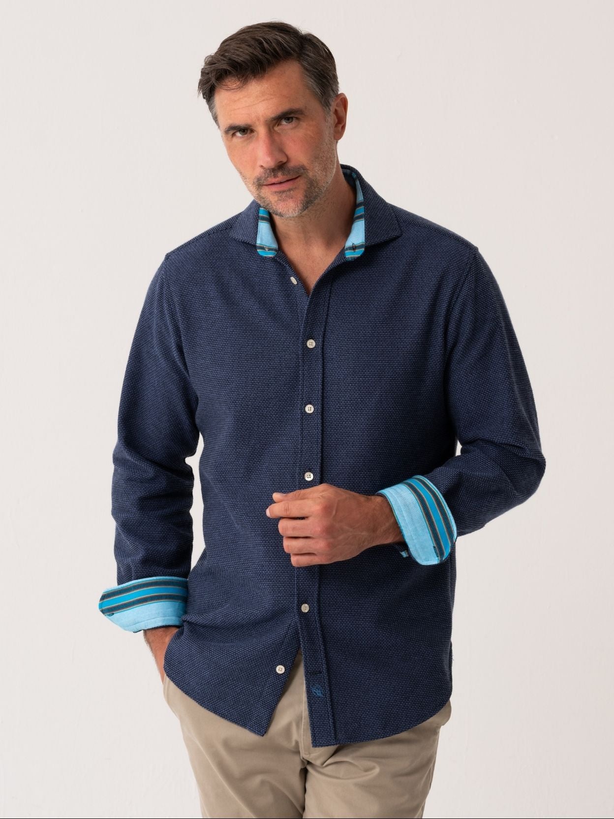 Man wearing a navy shirt with blue trim on a white background