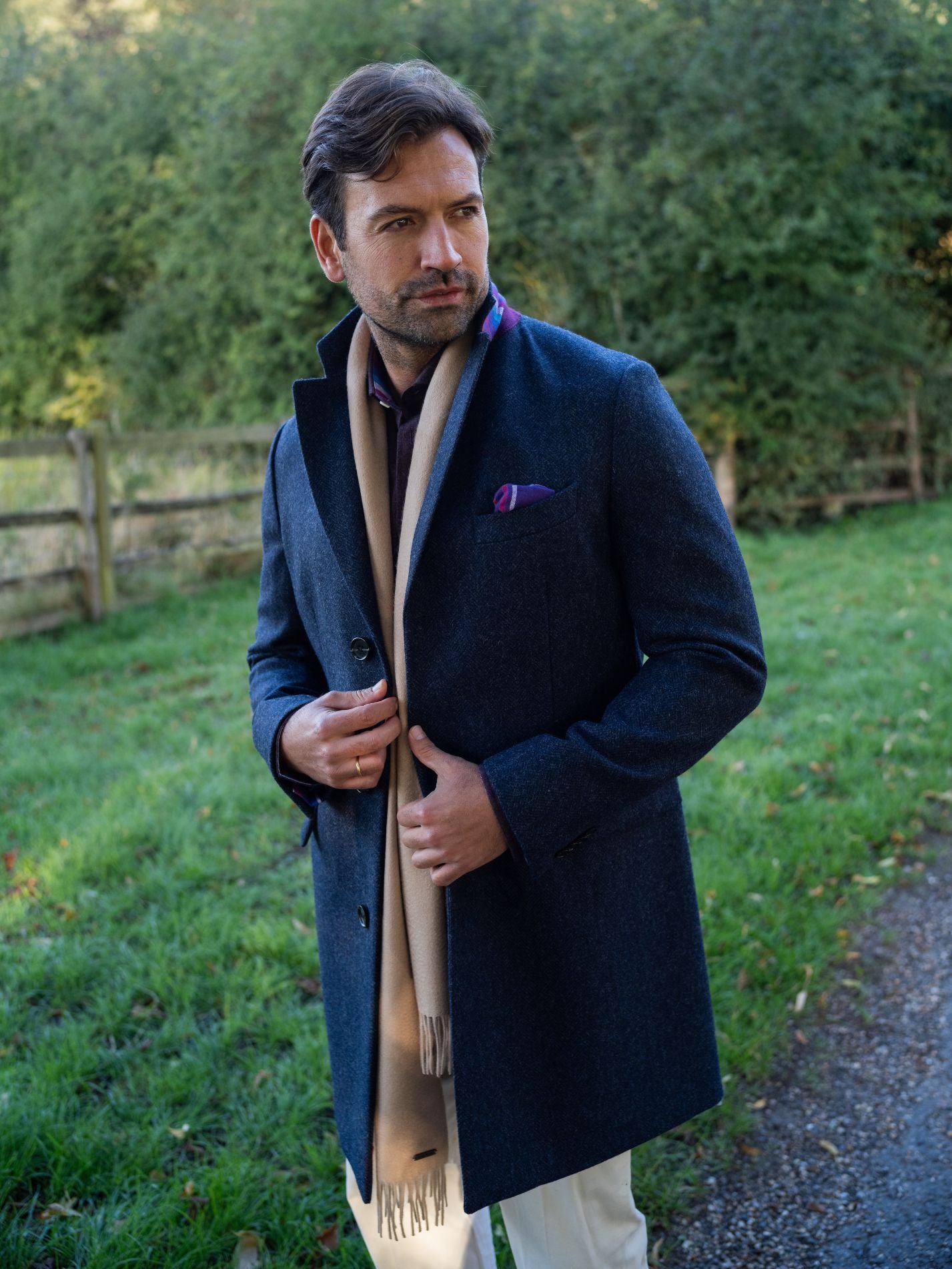 Man wearing a navy wool overcoat with a scarf in an outdoor setting