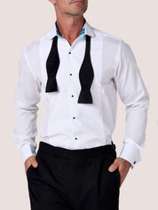 Koy white dress shirt with black bow tie loosely untied, hands in trouser pockets
