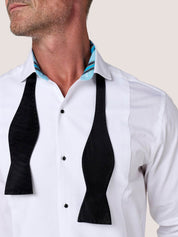 Close-up of the Koy dress shirt wing collar with black bow tie untied, showing the blue Kikoy-striped lining
